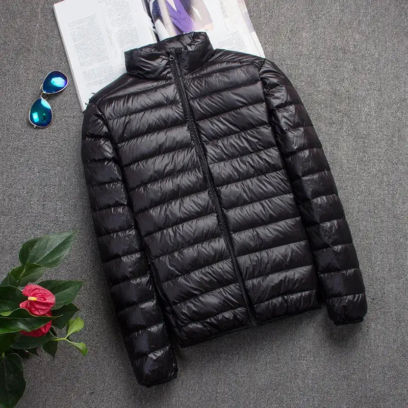 Men's black hooded puffer down jacket, ultra-light, slim-fit coat; blue sunglasses, magazine and pink plant nearby