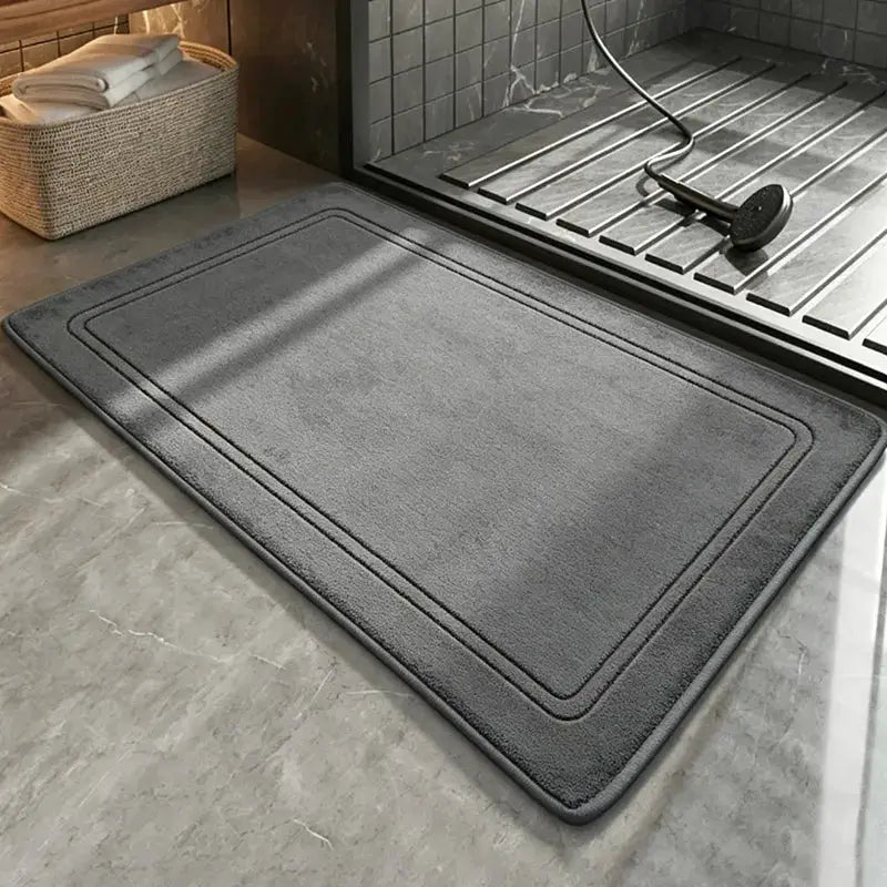 Grey bathroom rug with plush texture and bordered edges placed by the shower on a tiled floor