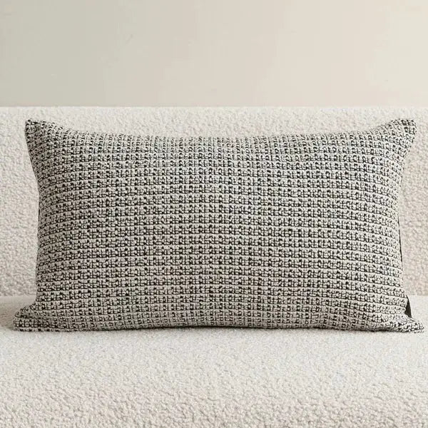Decorative pillow cover in ivory and black woven pattern on beige sofa.
