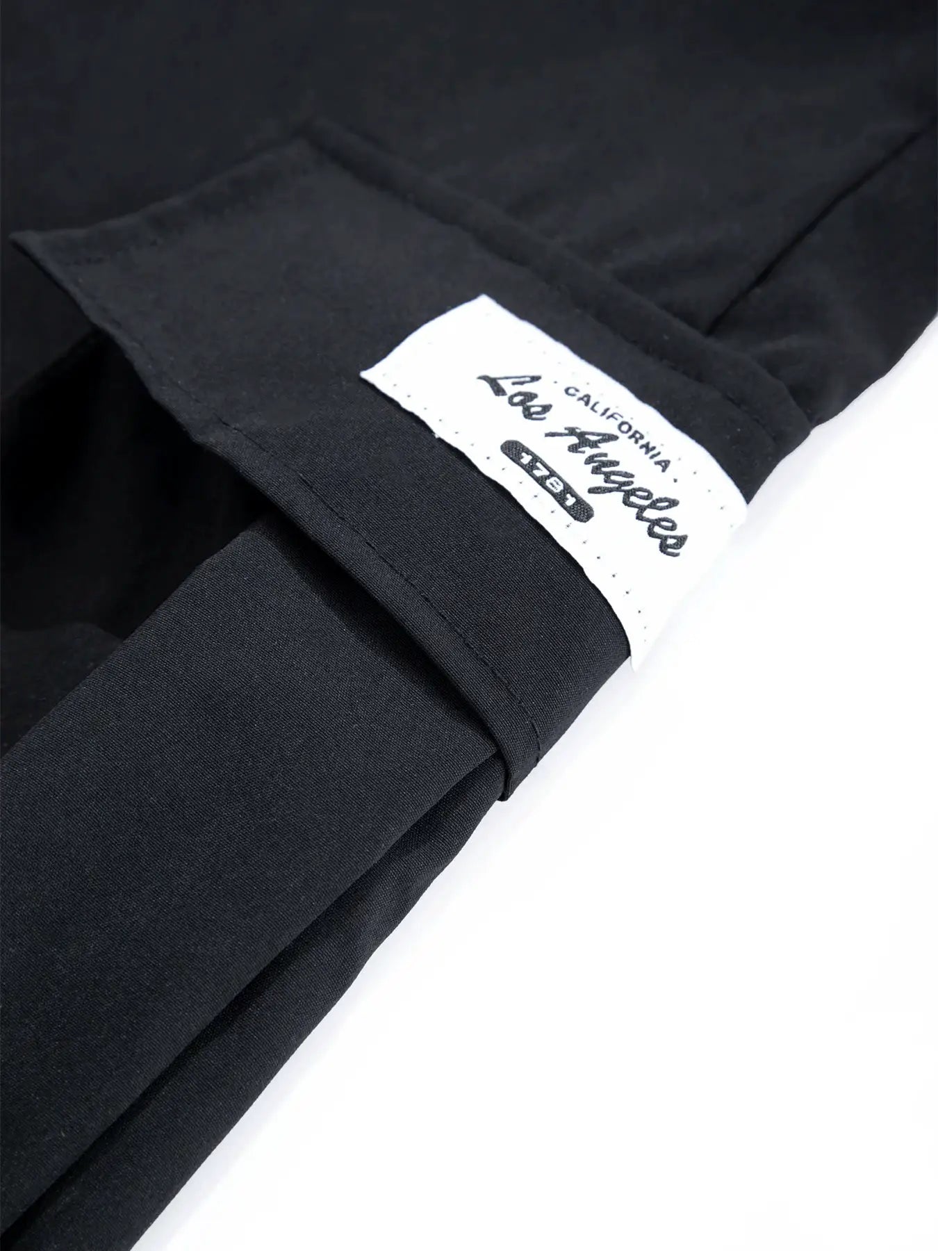 Men's black cargo pants cuff with white Lee label tag on hem
