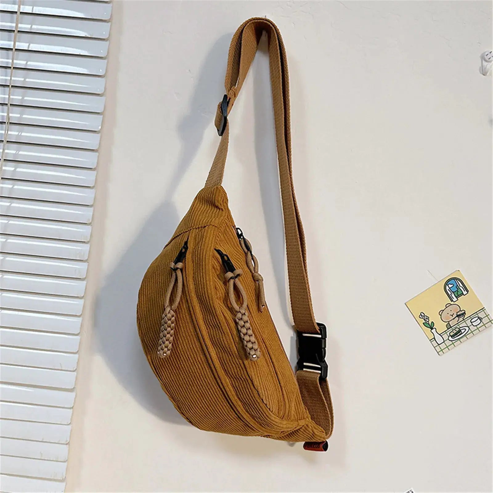 Women's brown corduroy belt bag with wide adjustable strap and decorative tasseled cords