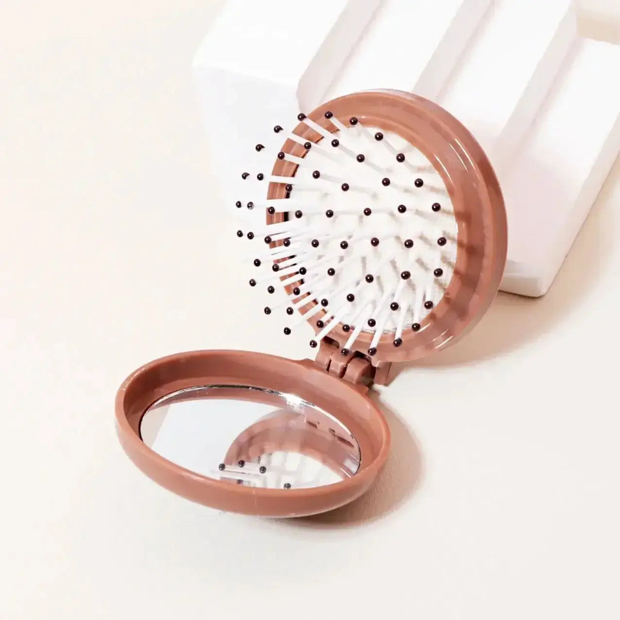 Rose gold mini folding travel hair brush with built-in mirror and anti-static bristles.