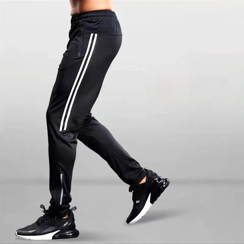 Men's black jogging pants with white side stripes and ankle zip details