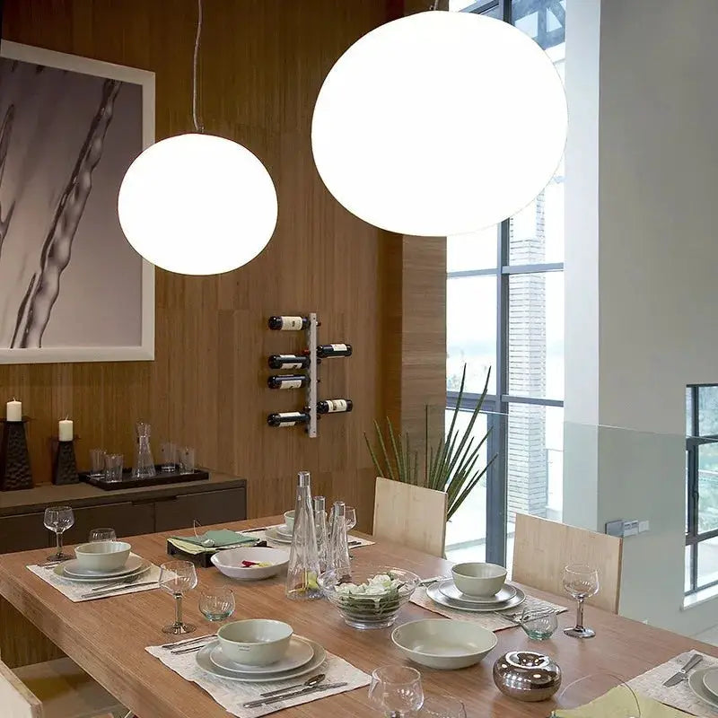 Two white glass ball pendant lights over a wooden dining table in a modern Nordic dining room