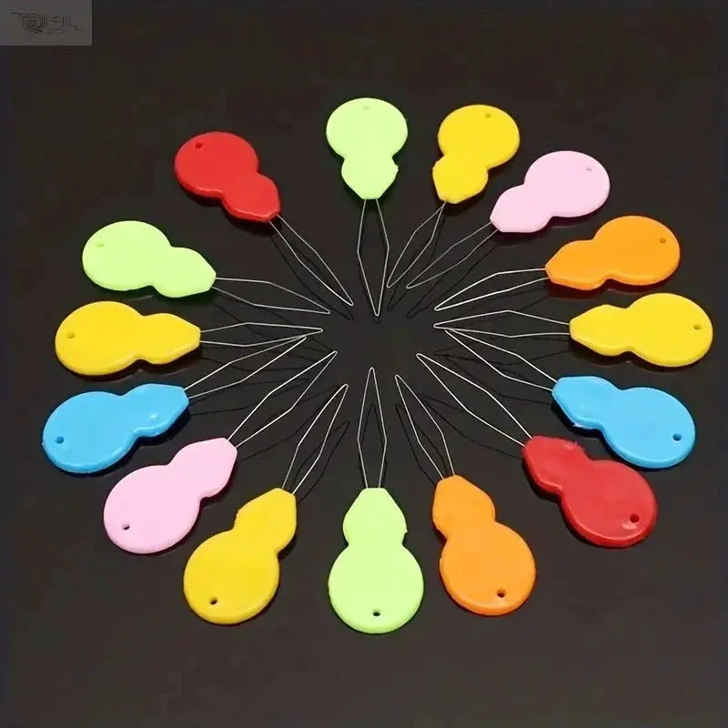 Plastic needle threaders by Simples Market in assorted bright colors, circular arrangement.
