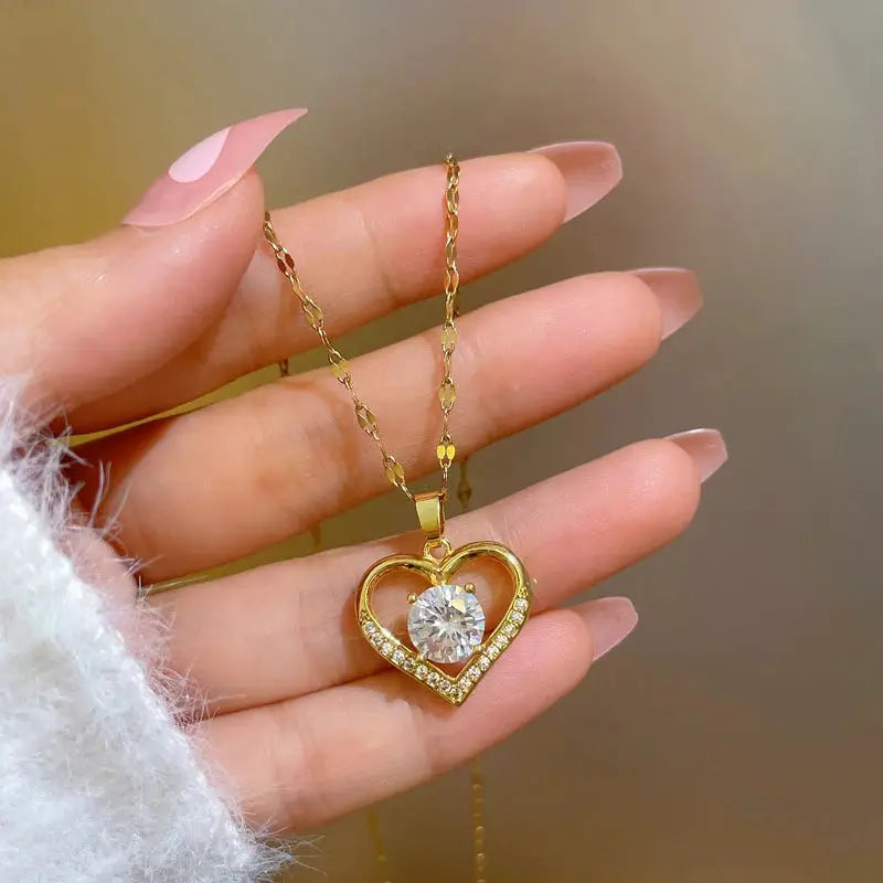 Gold heart pendant necklace with large clear center gem and pave-stone outline on a gold-tone steel chain