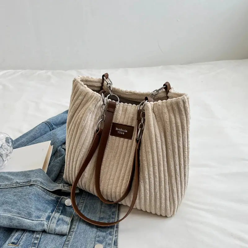 Beige corduroy shoulder bag with brown leather straps and metal chain accents, large-capacity casual handbag.