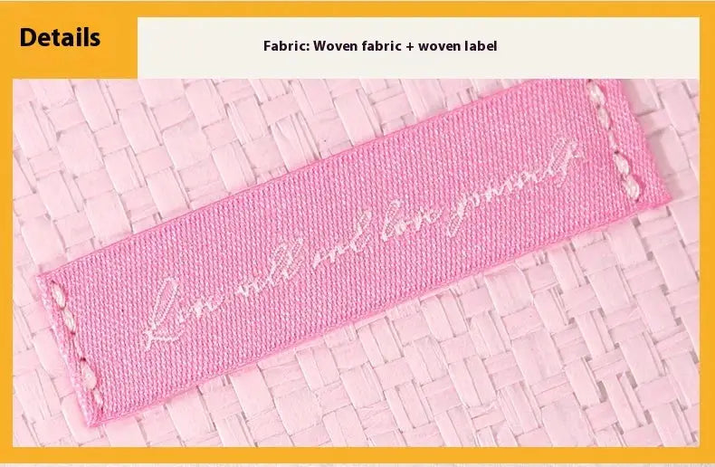 Pink woven fabric label with Simples Market script and stitched ends on a textured background