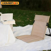 Beige foldable camping chair with backrest cushion on snow, for outdoor use; Homefish logo visible.