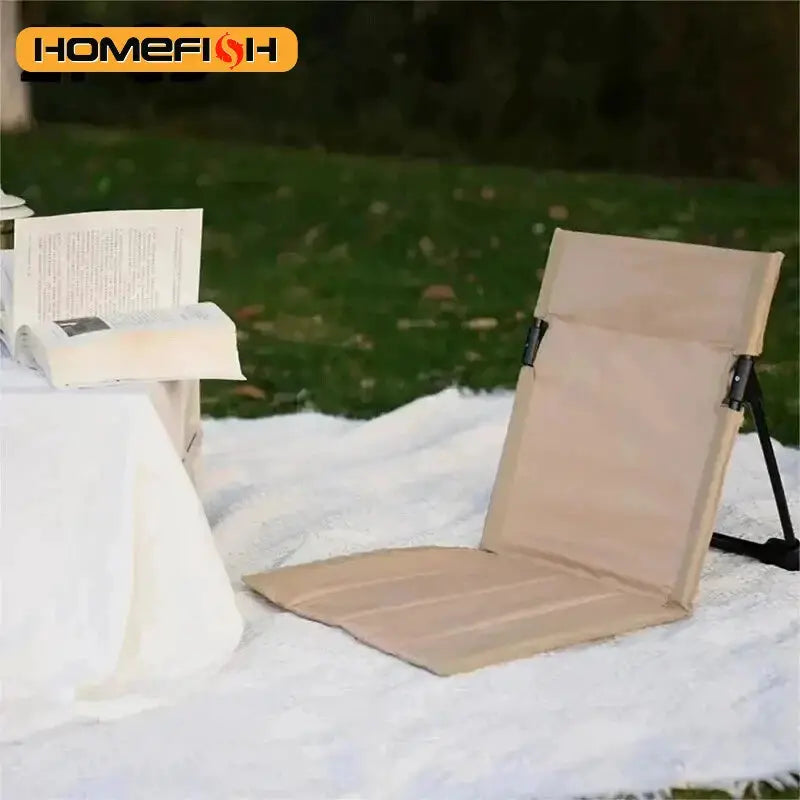 Beige foldable camping chair with backrest cushion on snow, for outdoor use; Homefish logo visible.