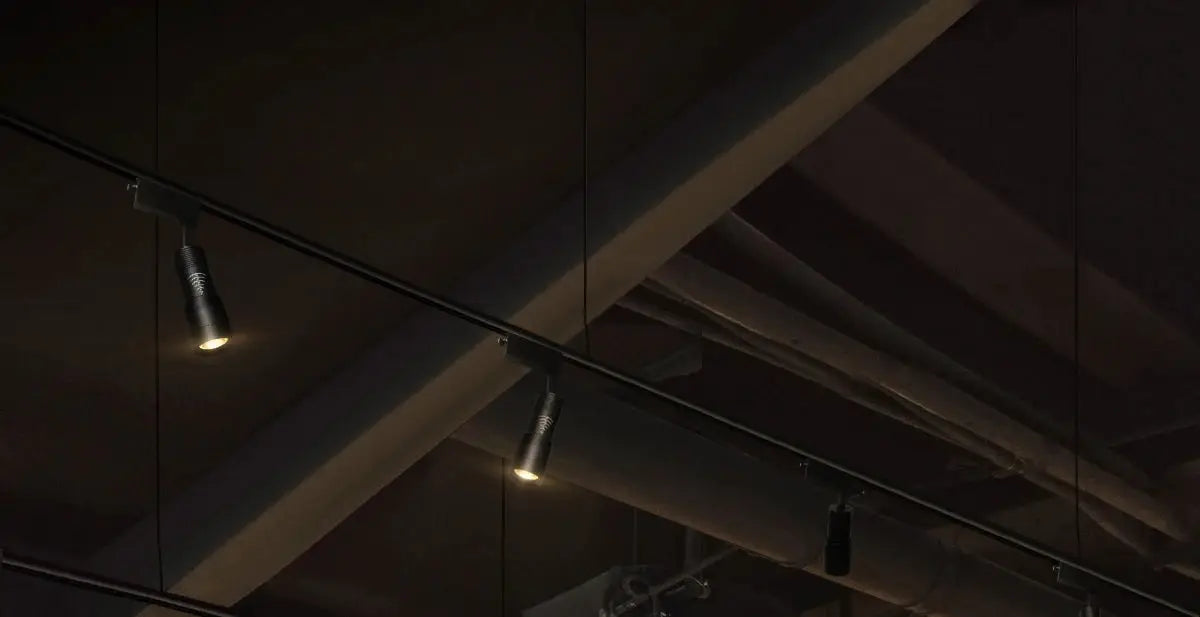 Three black surface-mounted ceiling LED spotlights on black track; Simples Market 7W zoomable, adjustable 5°~60° beam.