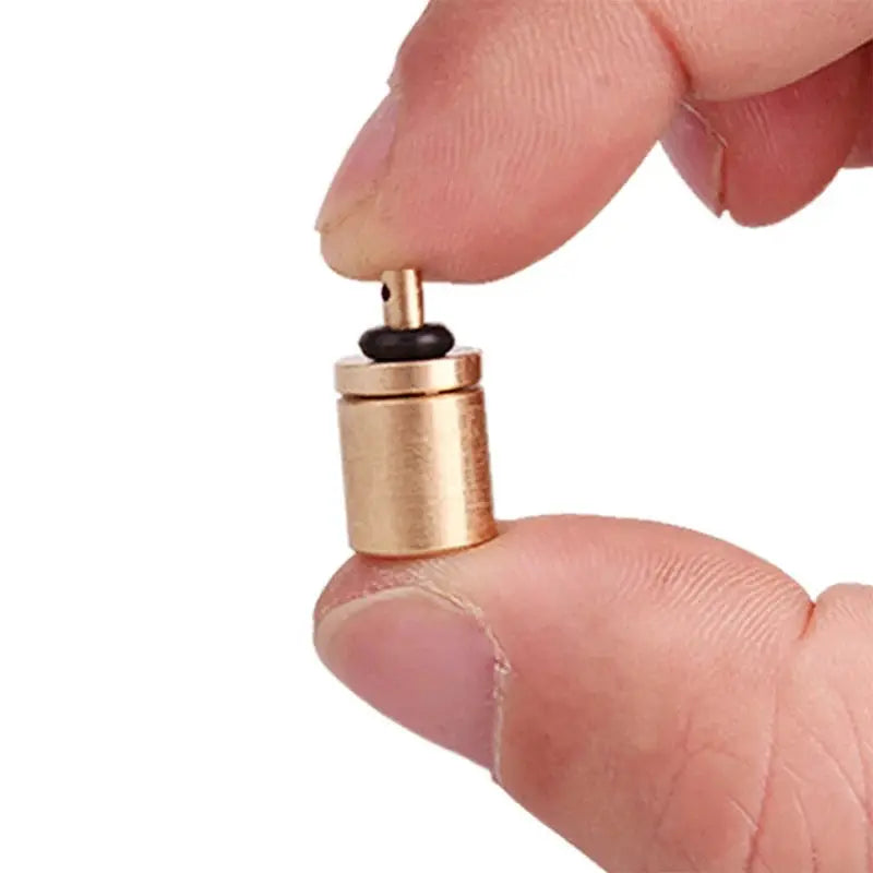 Copper gas tank adapter for outdoor camping stoves with spare O-rings, held by fingers.
