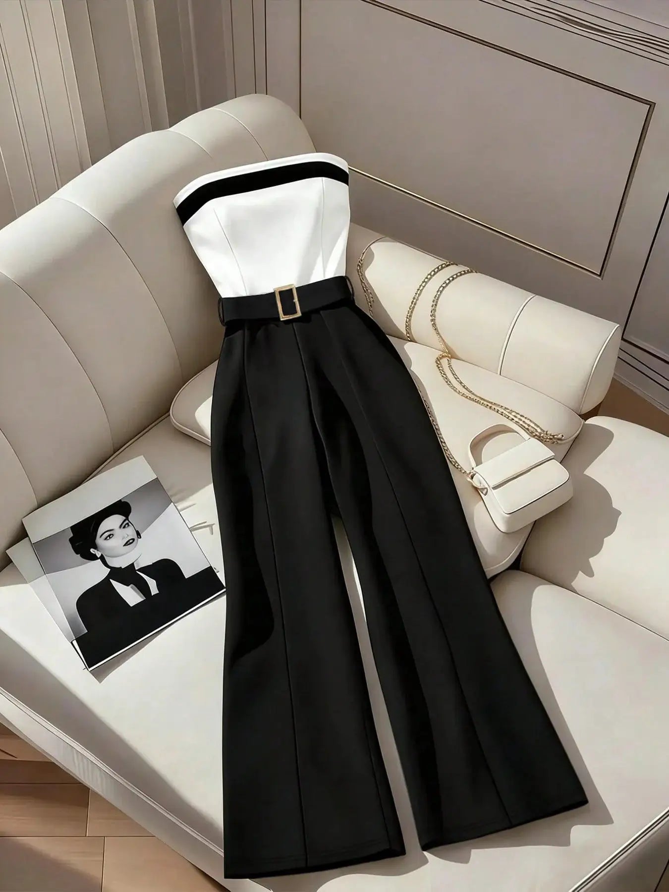 Women's black and white jumpsuit with square neckline, contrast trim, and belt; wide-leg pants.
