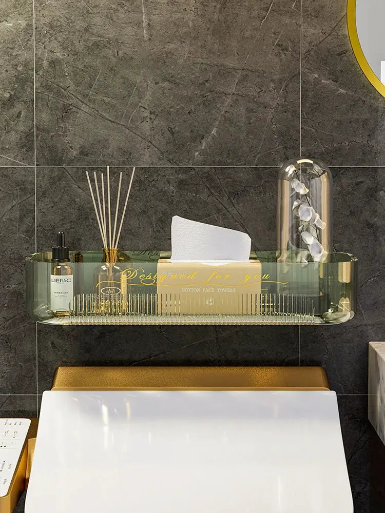 Clear acrylic bathroom storage rack with tissue box, bottles and diffuser, wall-mounted above toilet.
