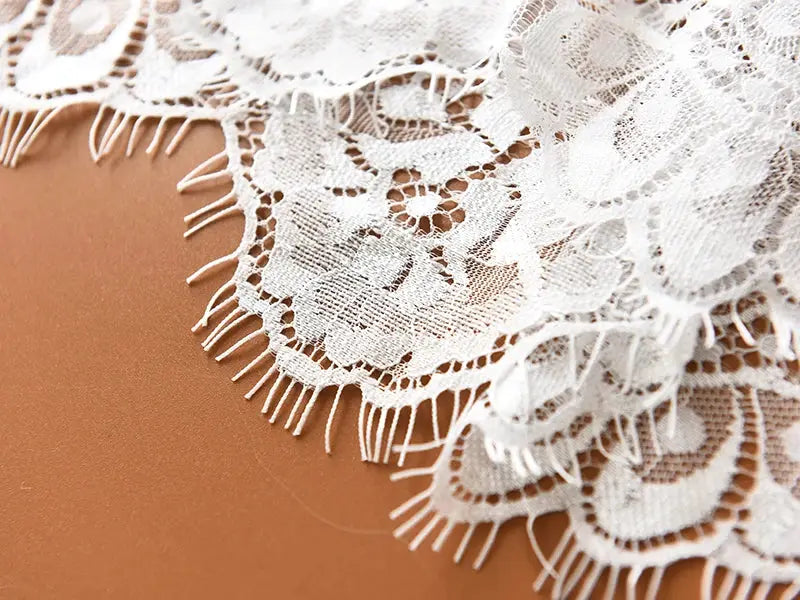 Lace fabric close-up: white floral lace with fringe edging for a beach midi skirt