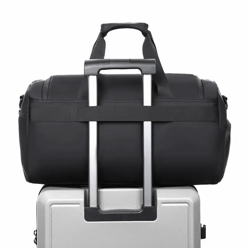 Gym bag, black, large-capacity with shoe storage, perched on a silver rolling suitcase