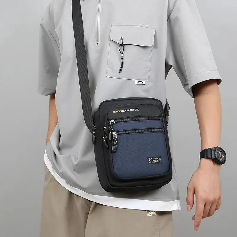 Simples Market Oxford men crossbody bag with multiple pockets, navy blue front panel and black trim.