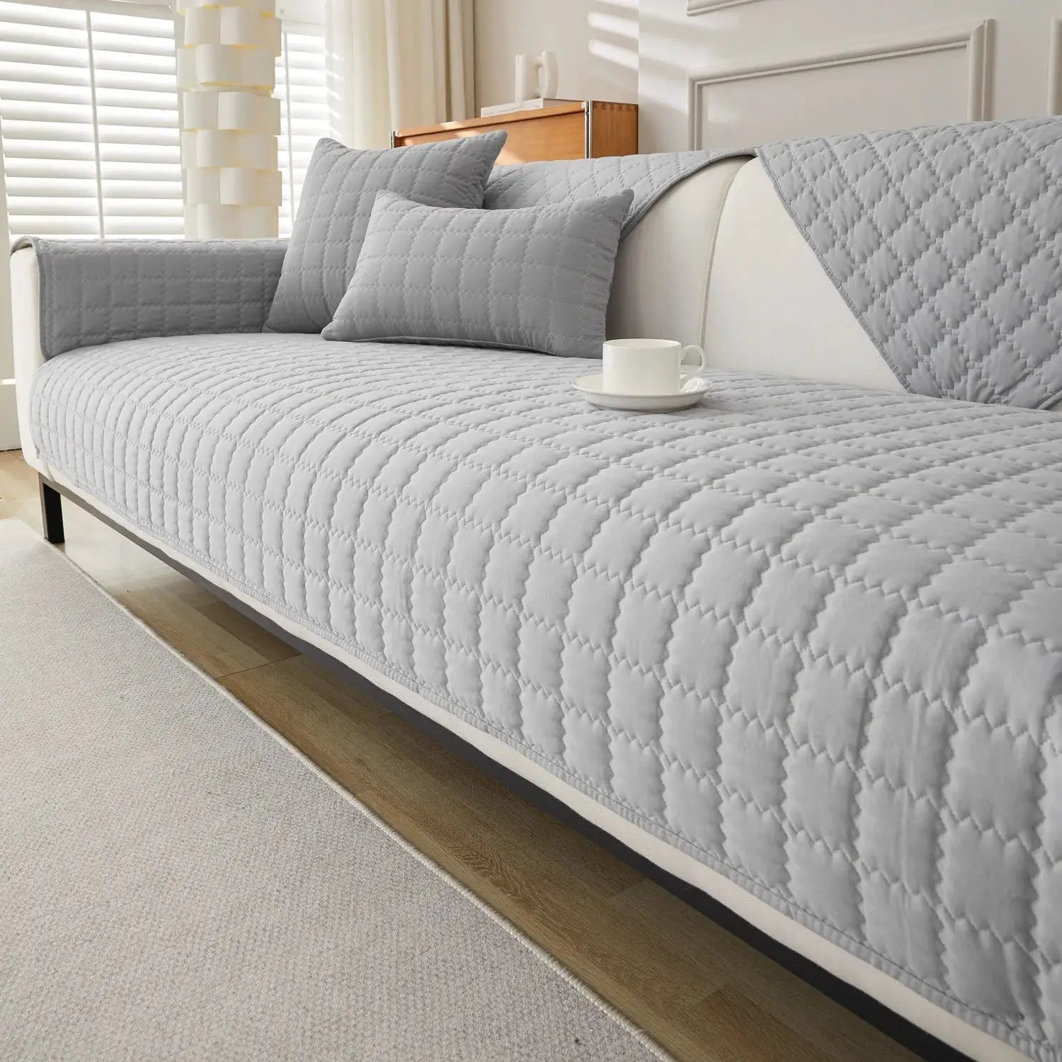 1pc quilted anti-slip sofa cover in light gray by Simples Market on a modern sofa