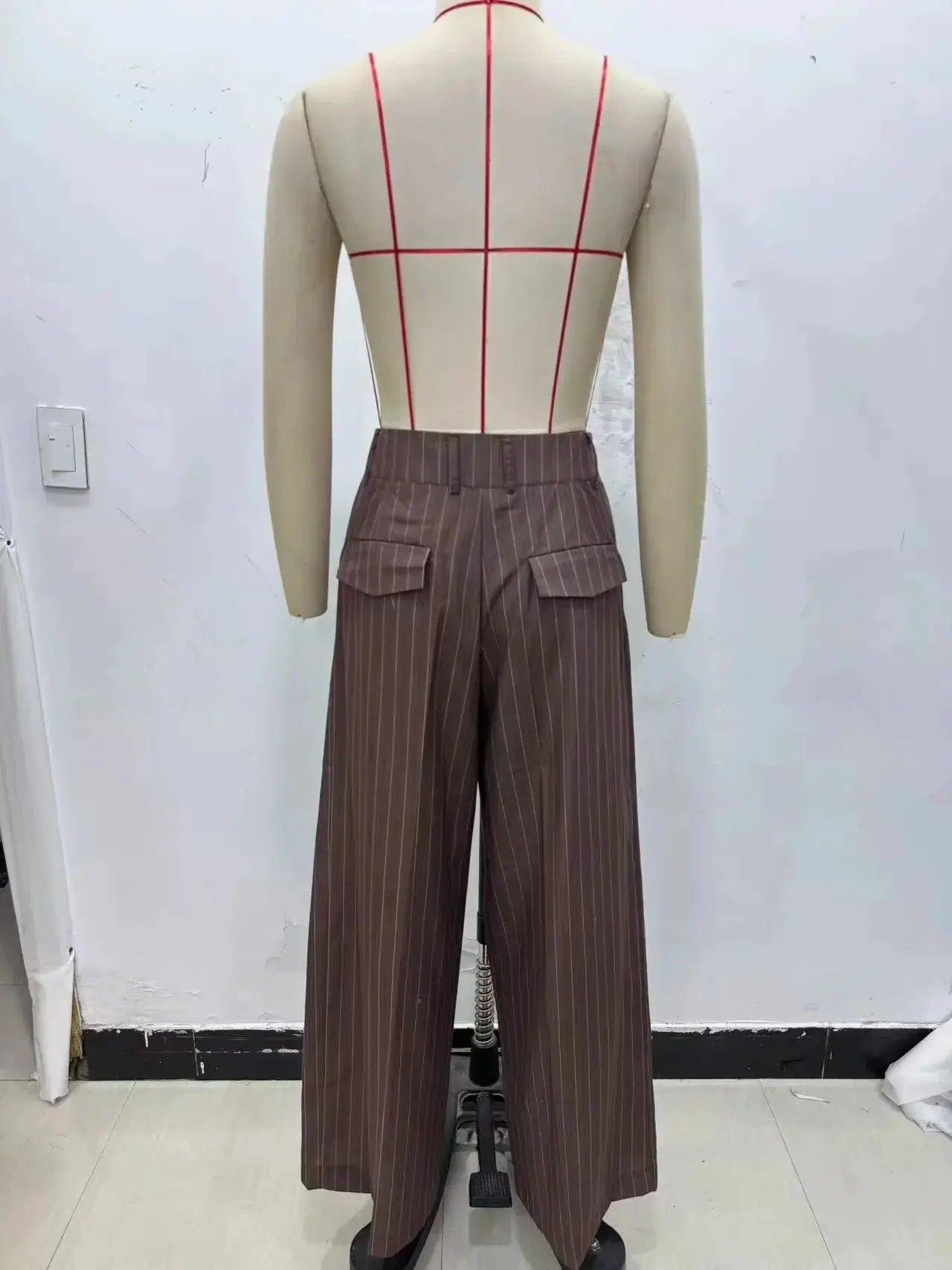 Wide-leg brown pinstripe pants with flap pockets on a mannequin back view