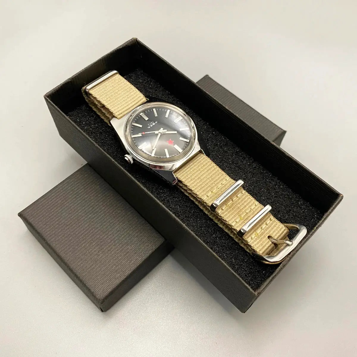 Mens mechanical watch with beige fabric NATO strap, stainless steel case, black dial in box