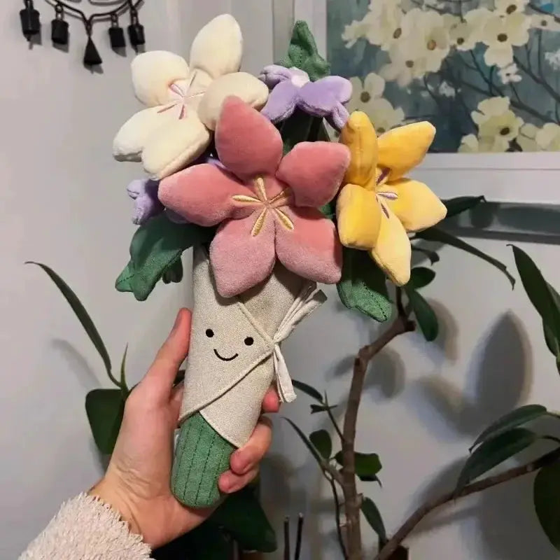 Simples Market plush bouquet of pastel flowers with a smiling paper-wrapped stem, held in hand