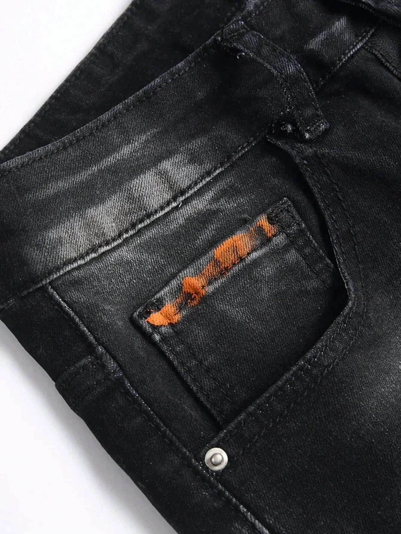 Men's black denim shorts; close-up shows front pocket with orange stitched patch on dark fabric.