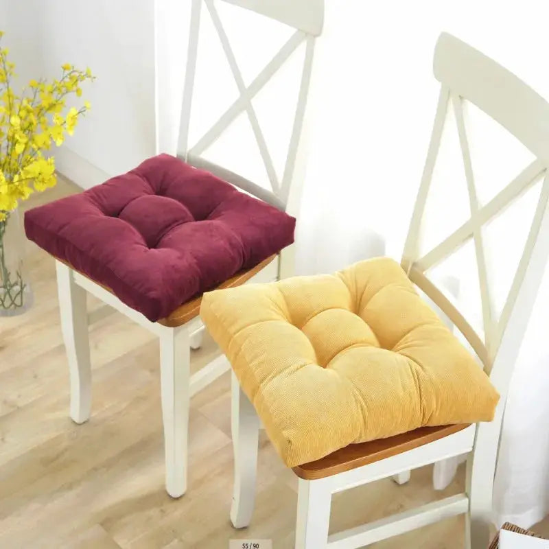 Floor pillows: two square tufted cushions in burgundy and mustard for seating on white chairs