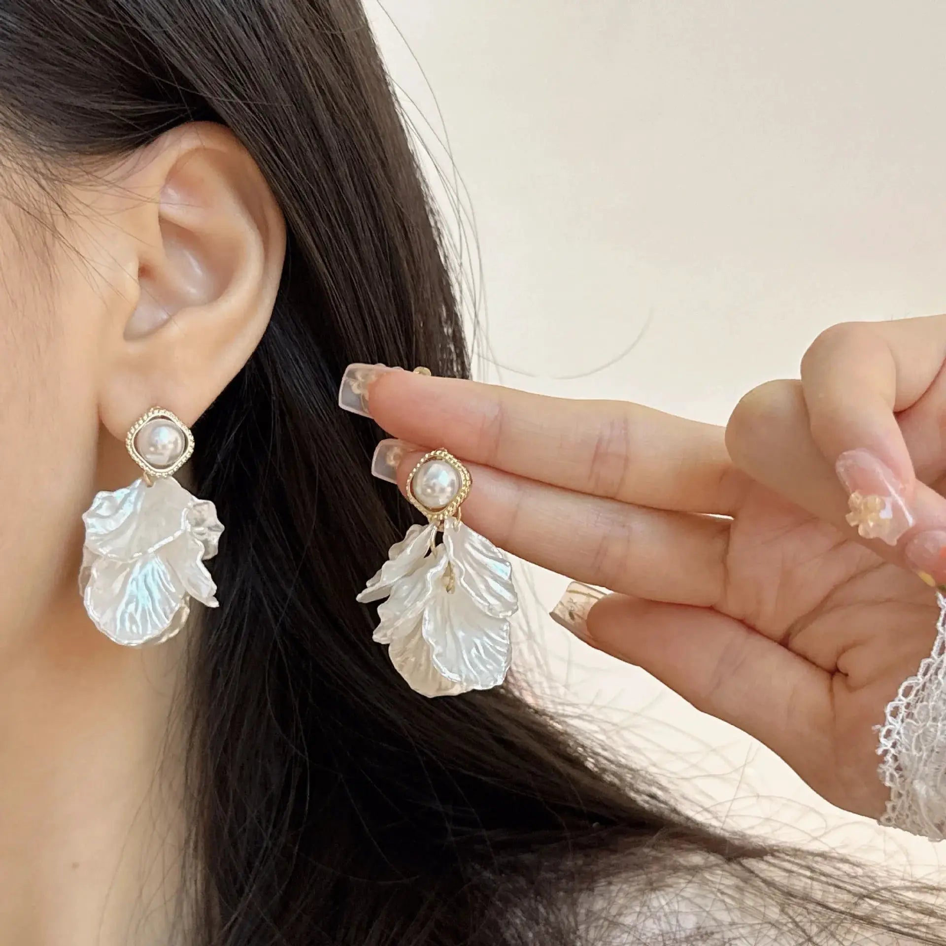 Pair of glossy shell flower pendant earrings with pearl centers in gold-tone bezel.