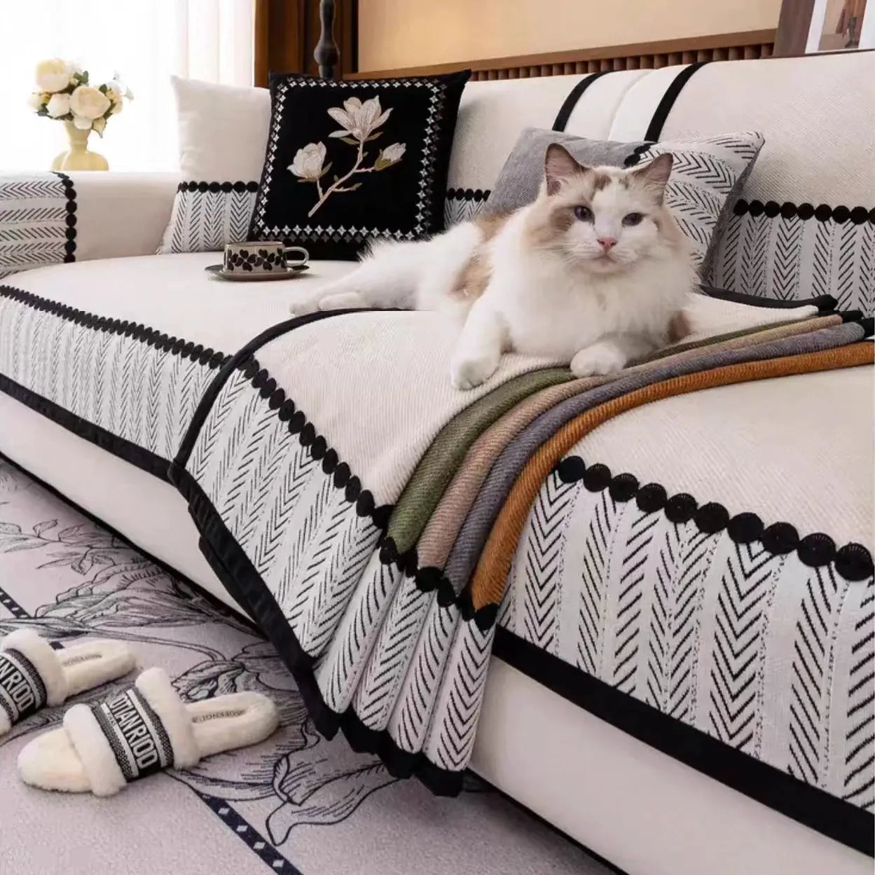 Sofa cover in cream chenille with black contrast hem on a patterned living room sofa, cat relaxing.