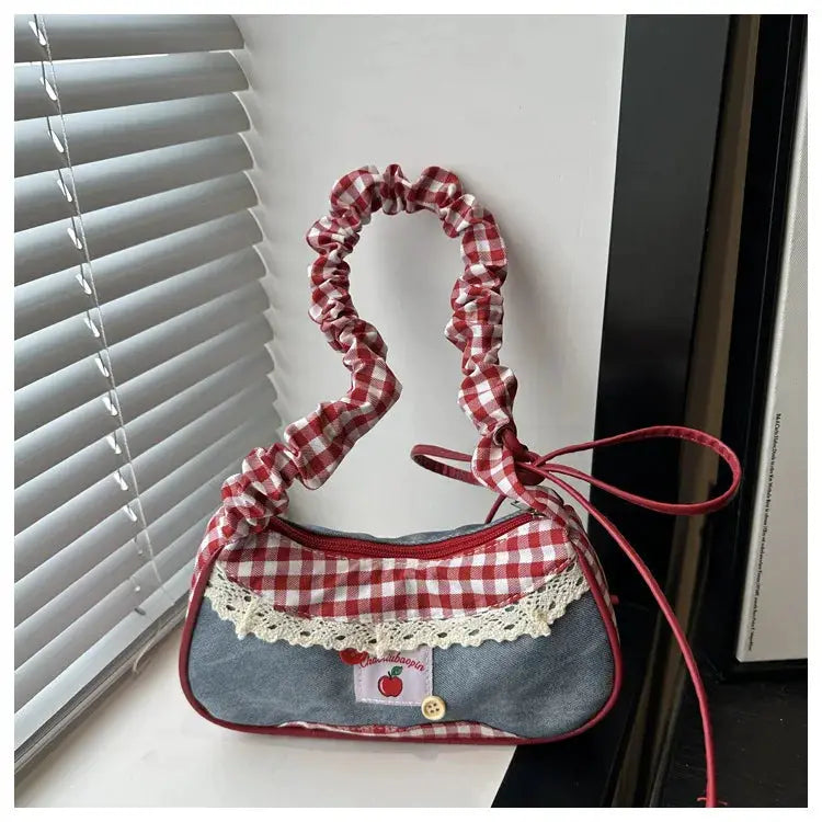 Casual hand-held bag with red gingham scrunchie handle, denim-blue body, and lace trim.