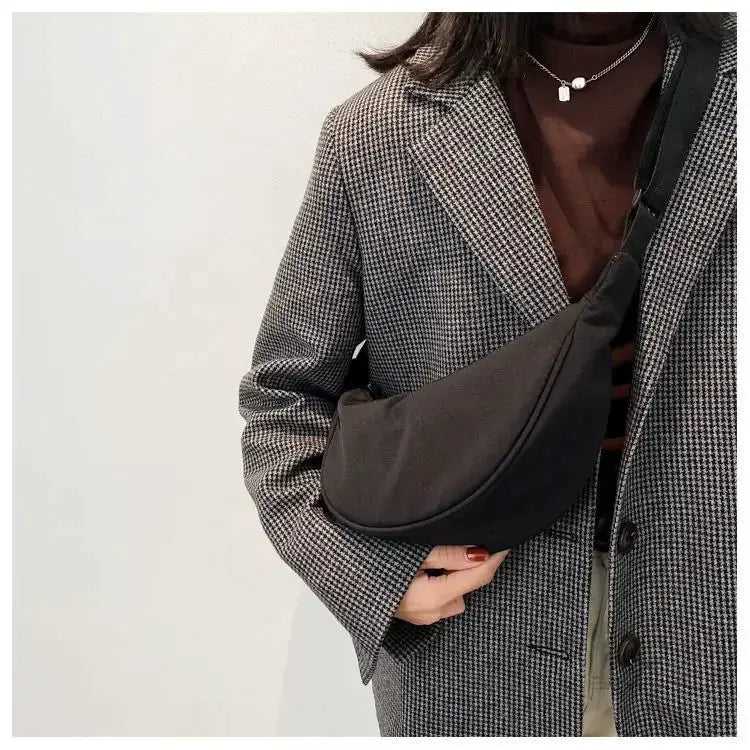 Nylon dumpling crossbody bag in black; compact, lightweight bag worn across the chest.