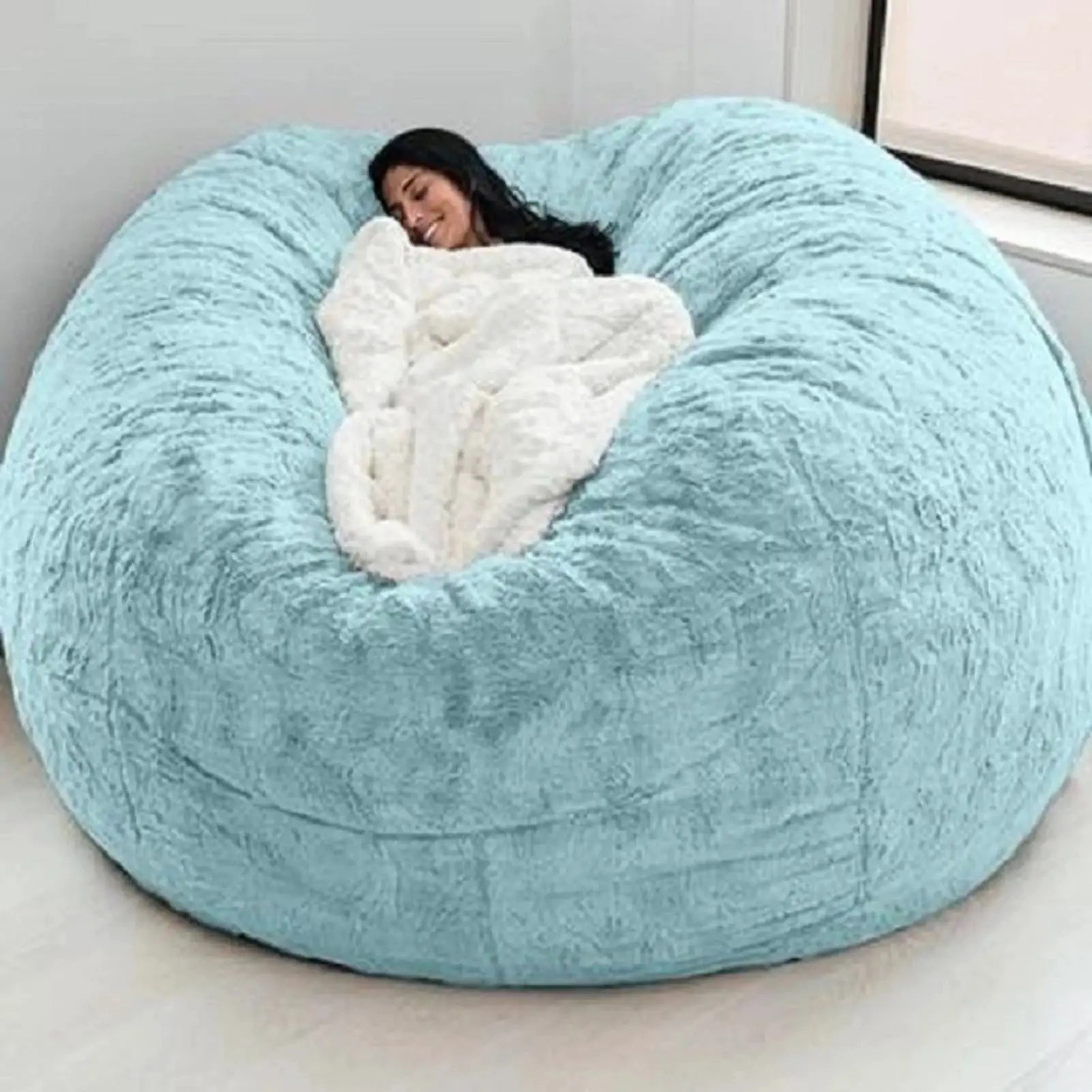 Giant blue bean bag sofa bed with white plush blanket