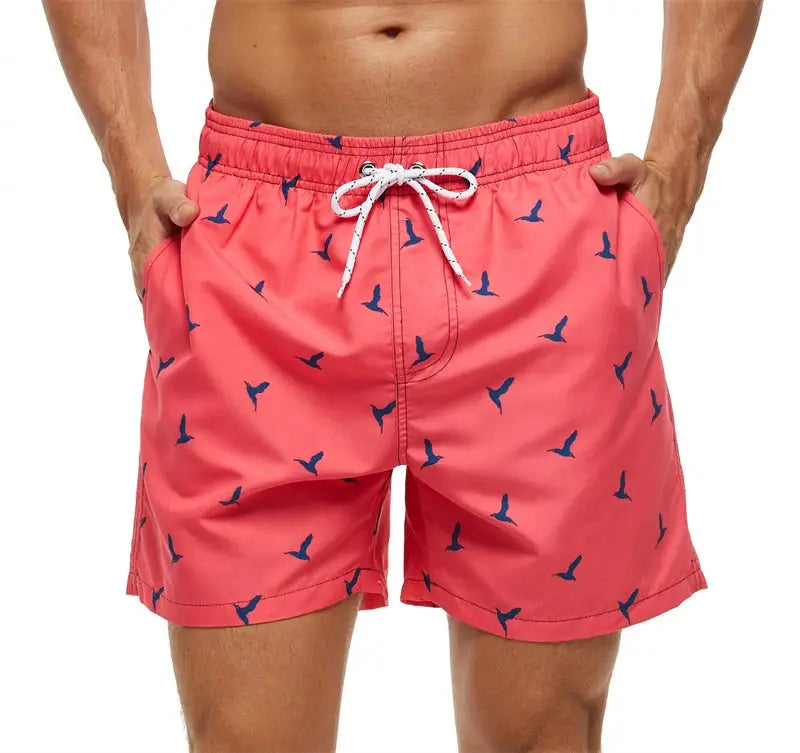 Men's coral swim shorts with blue bird print, white drawstring, and side pockets.