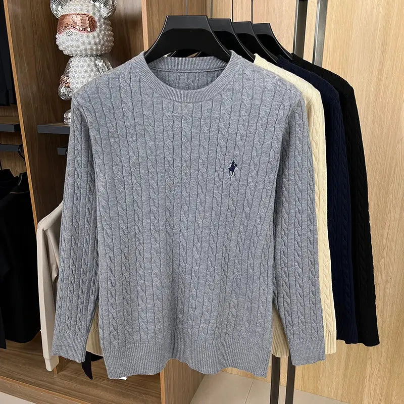 Grey cable-knit sweater with round neck and chest embroidery on display, with cream, navy and black options.