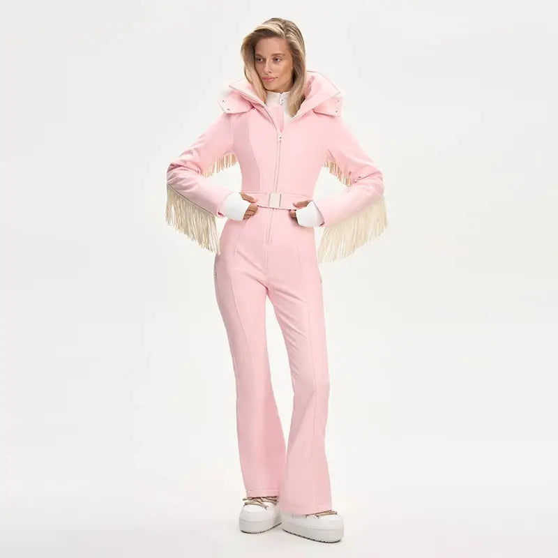Pink women's one-piece ski suit by Simples Market with faux-fur hood, fringe tassels and high-waist belt.