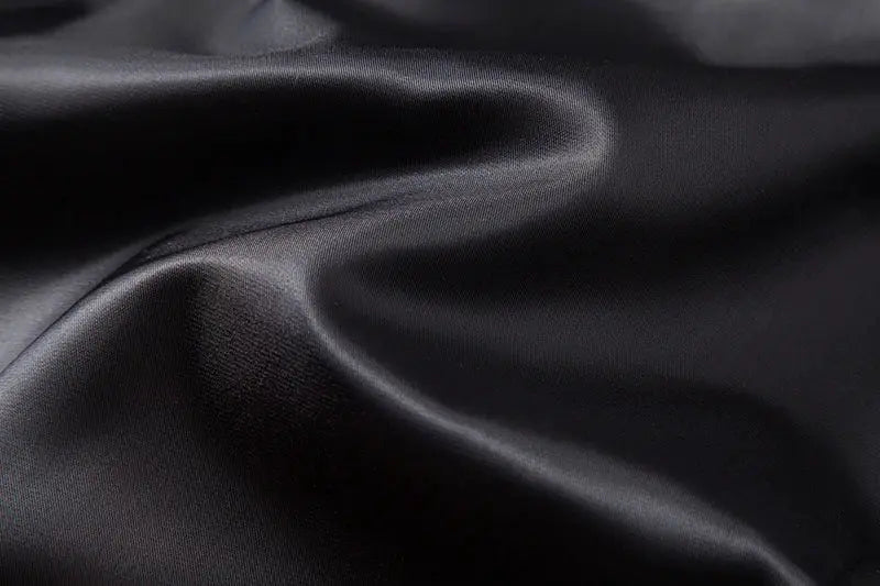Black satin vest fabric close-up with smooth folds