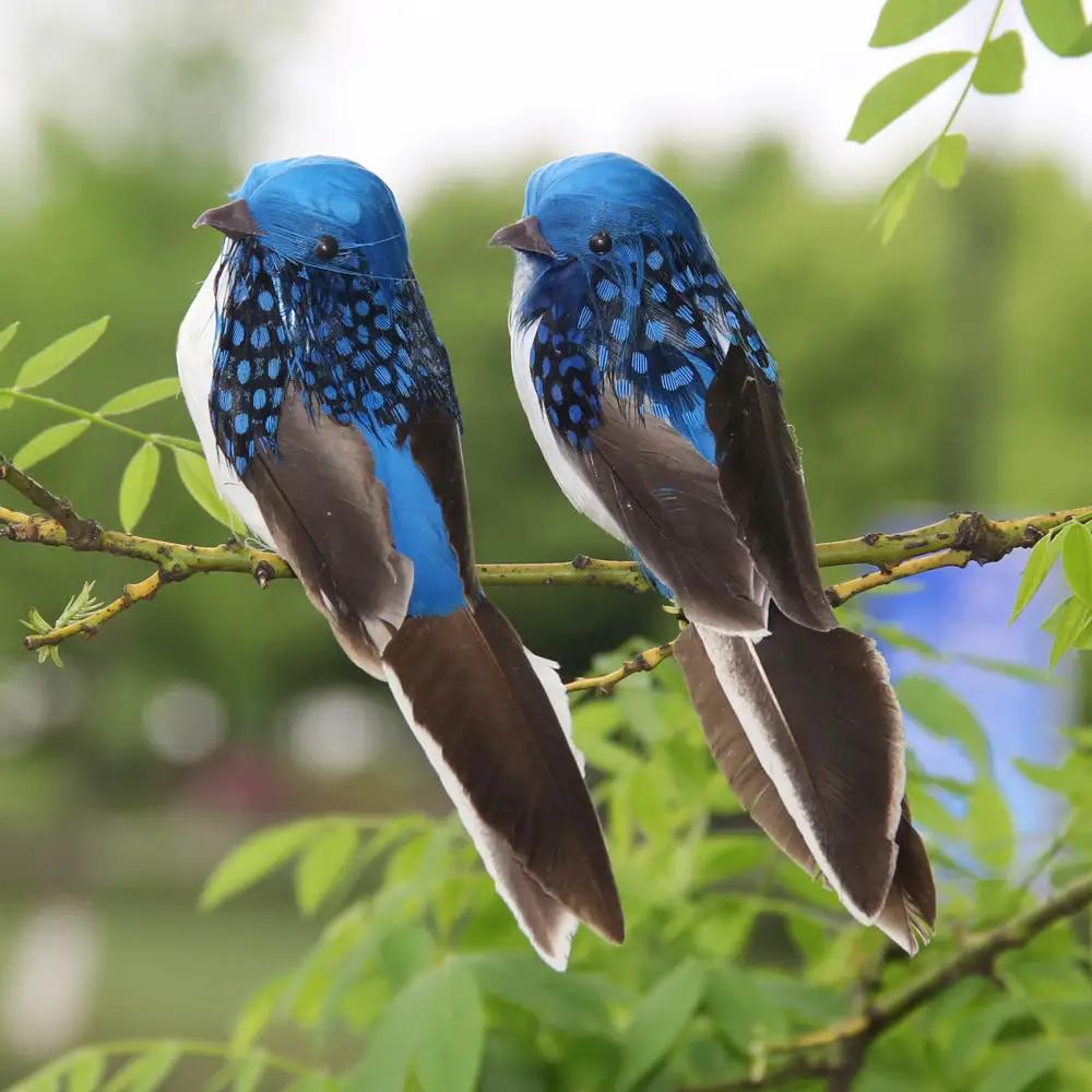 Two blue foam feather birds for garden decoration perched on a branch