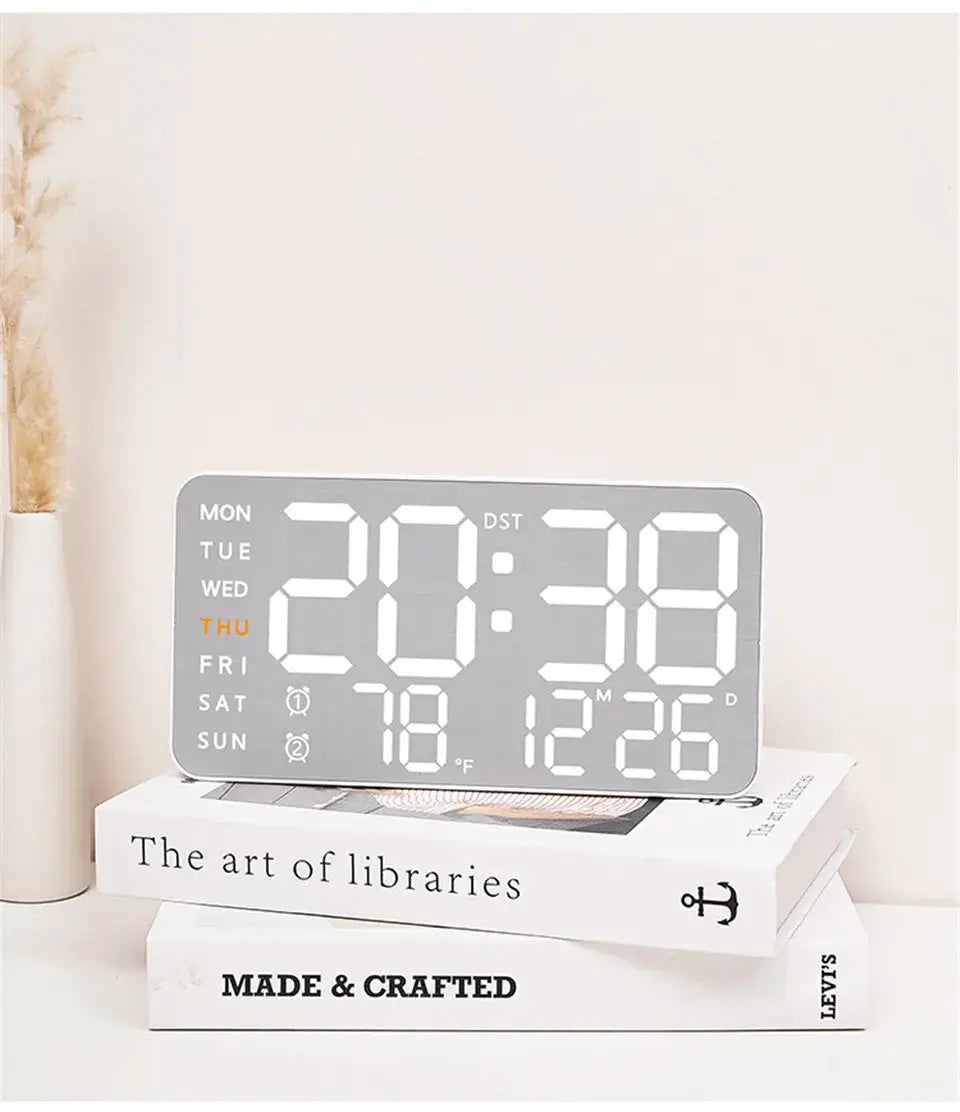 Mirror-brushed digital wall clock with large display and temperature readout on stacked books