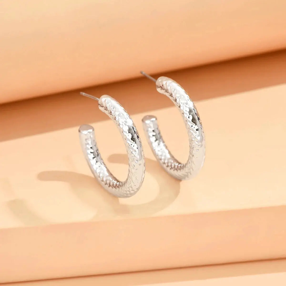 Silver hammered hoop earrings for women by Simples Market; metallic finish.