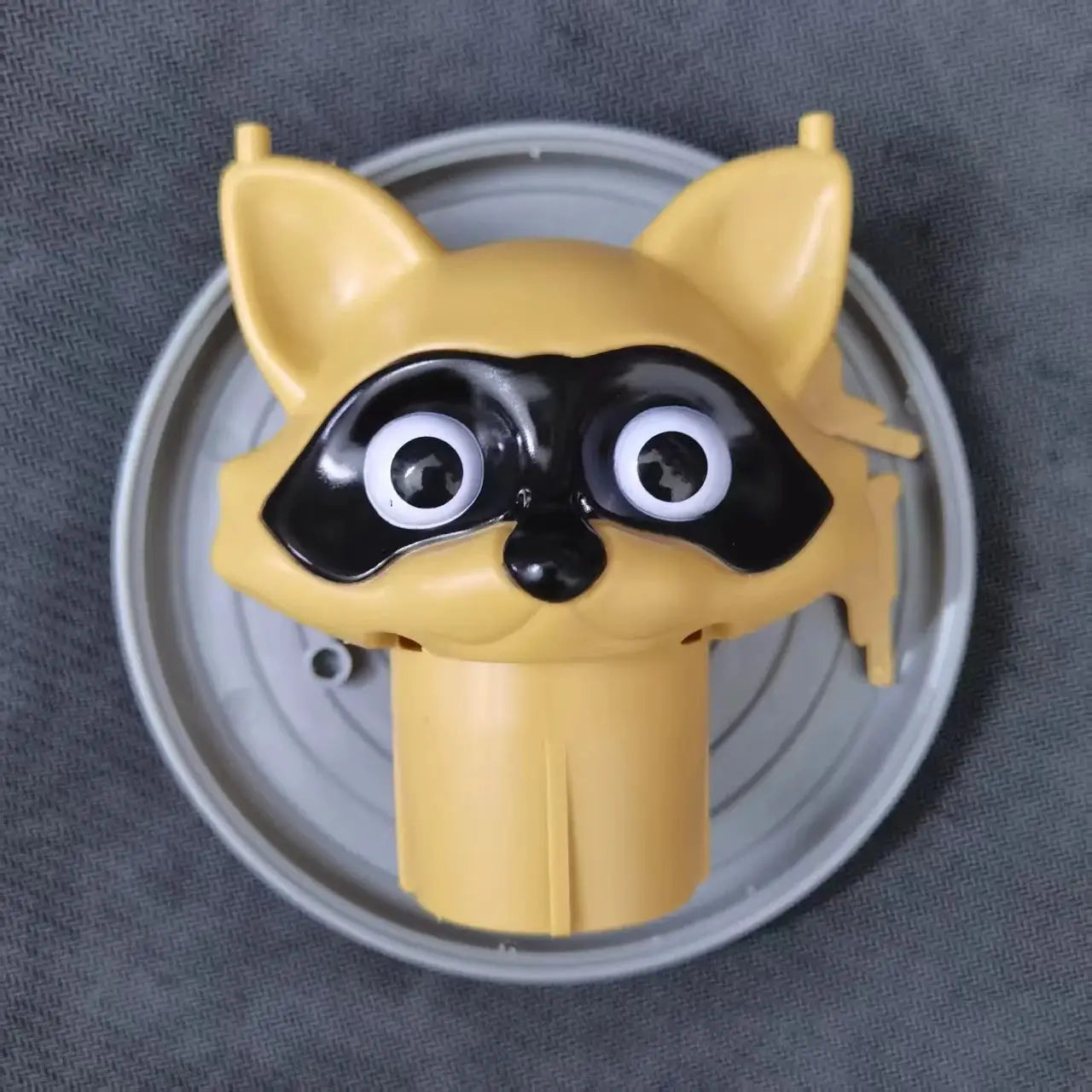 Toilet paper holder shaped as a yellow dog with a black mask and big cartoon eyes, decorative bathroom accessory