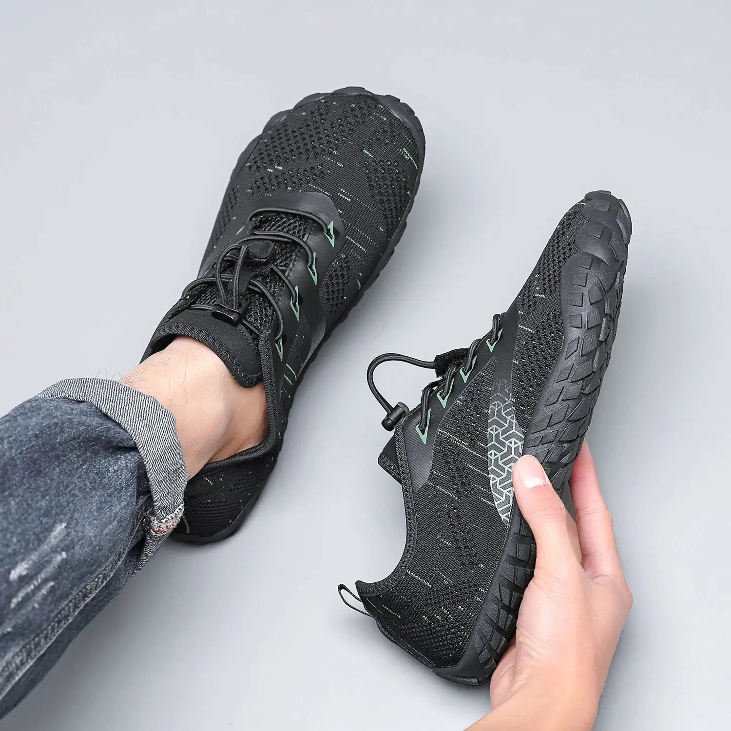 Men's trail running shoes with black knit mesh upper and teal accents, rugged outsole