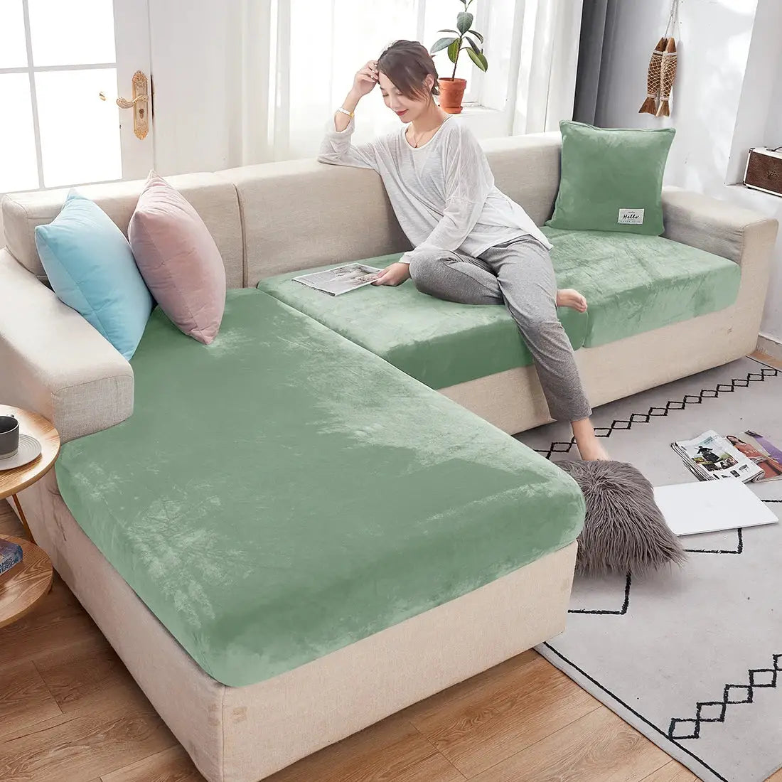One-piece plush sofa slipcover in emerald-green with anti-slip elastic fit, protecting beige sectional living room couch