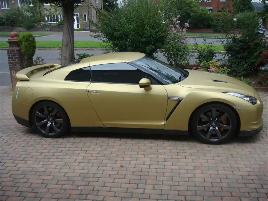 Matte gold wrap vinyl film on a gold sports car with dark wheels and rear spoiler