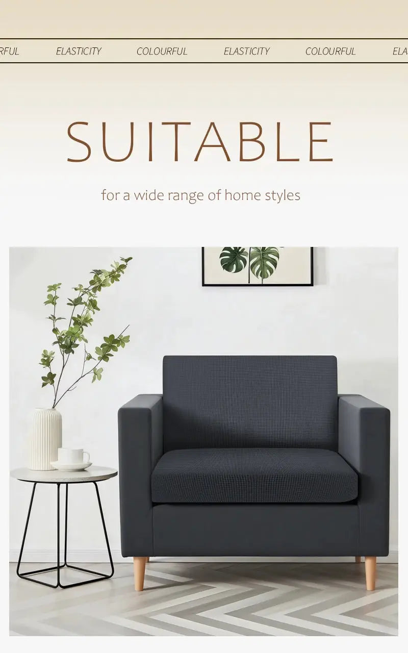 Dark gray upholstered armchair with light wooden legs in a modern living room, beside a round side table and plant.