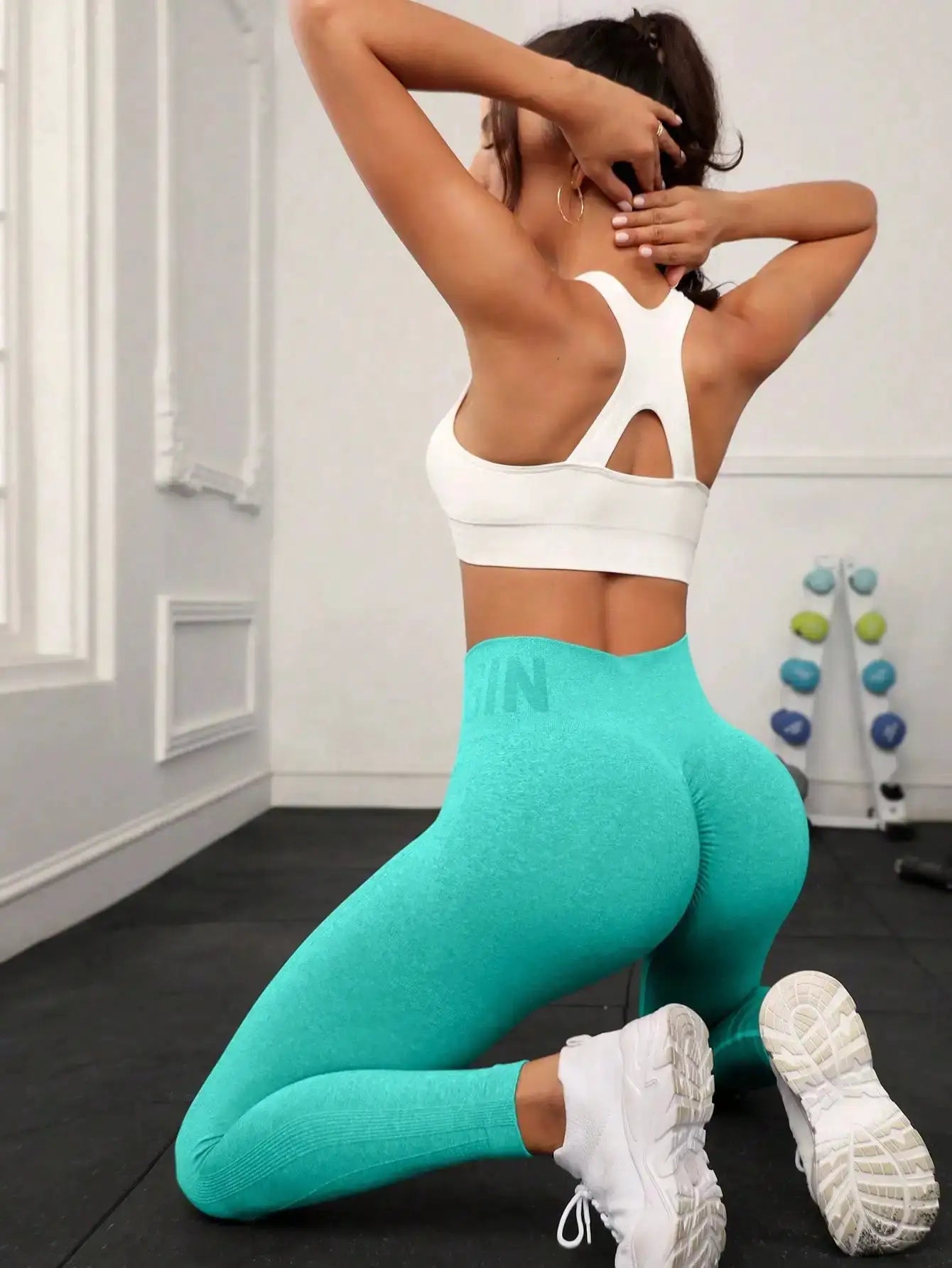 Seamless high-waisted turquoise yoga pants worn by a woman in a gym