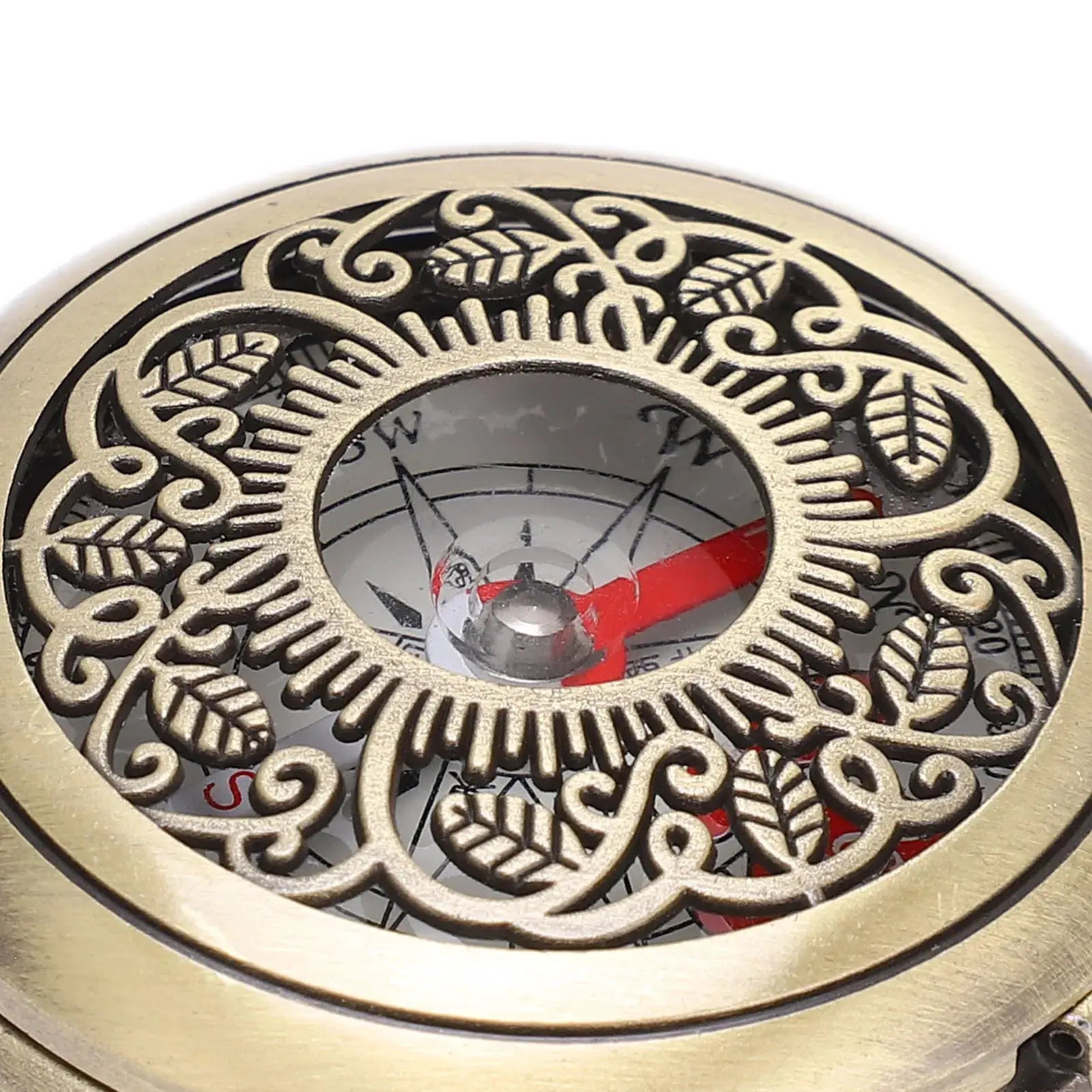 Brass compass with ornate cut-out ring and red needle for outdoor navigation