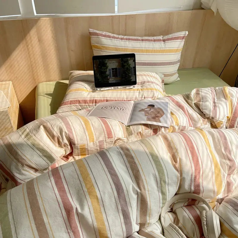 Cotton striped bedding set with duvet cover and pillowcases in pastel yellows, pinks, and creams on a bed