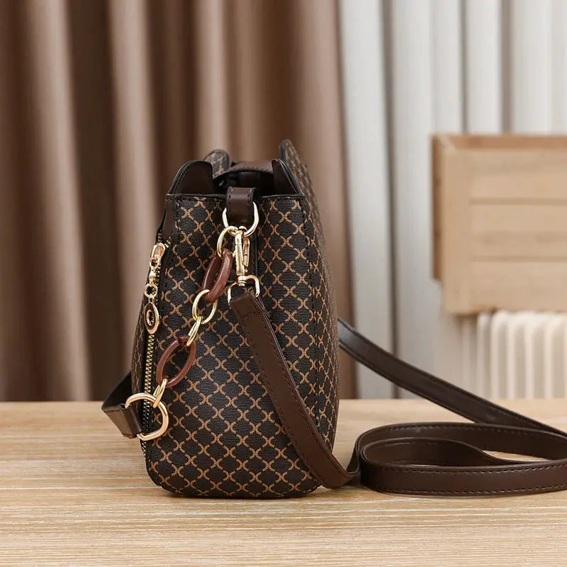 Bucket crossbody handbag with brown check print, gold hardware, and brown leather strap