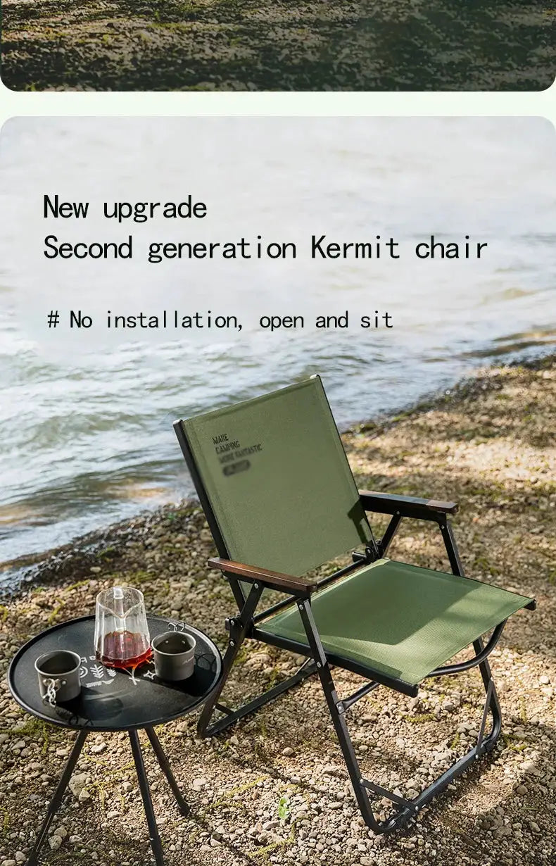 BISINNA outdoor folding camping chair with green fabric and black frame beside a round table on a rocky lakeshore