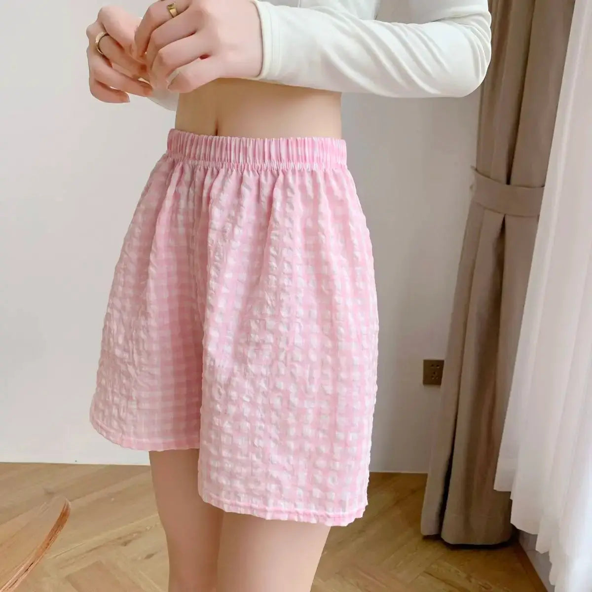 Women's pink plaid high-waisted pajama shorts with elastic waistband and loose wide legs.